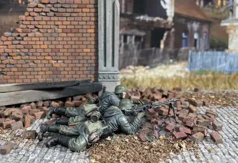 Two miniature soldiers in a battle pose on a textured surface with a brick wall and destroyed building in the background.