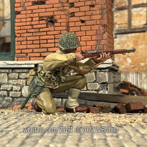 Collectible toy soldier army man U.S. Infantryman Kneeling Firing M1 Garand. He is next to a brick wall.