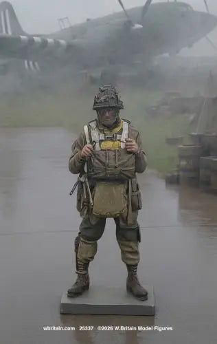 A detailed scale model figurine of a World War II British soldier standing on a base, set against a foggy, atmospheric background of a military airfield with a propeller plane.