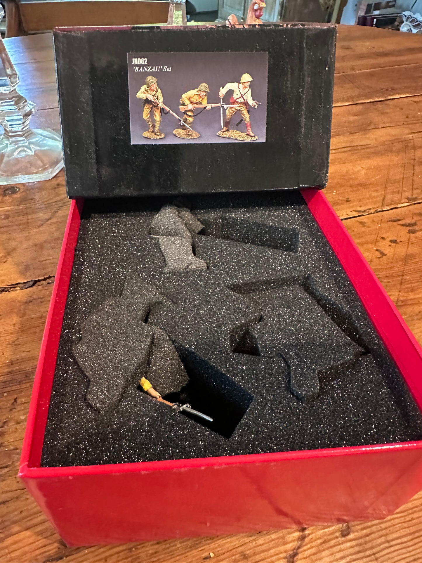 Open toy soldier box with a black item inside on a wooden surface