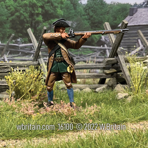 Collectible toy soldier miniature firing musket in a field.