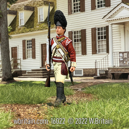 Collectible toy soldier miniature Grenadier NCO Marching. Soldier is marching in front of colonial home.