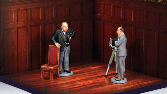 King & Country Churchill & The Roaring Lion set: Winston Churchill scowling with one hand on a chair while photographer Yousuf Karsh stands at his camera and tripod in a wood-panelled room