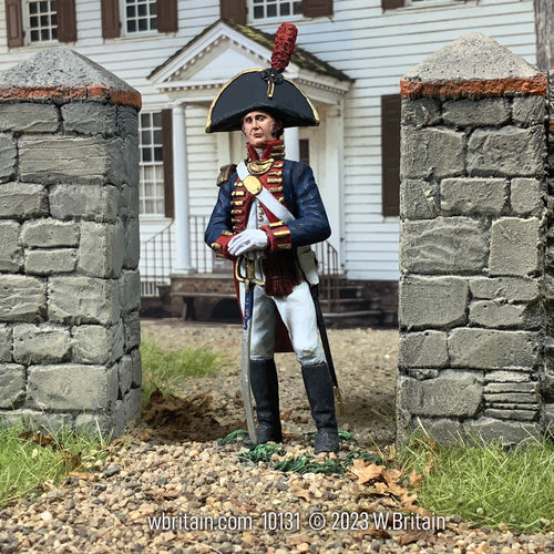 Collectible toy soldier miniature William Clark outside in front of a white house and grey stone fence.