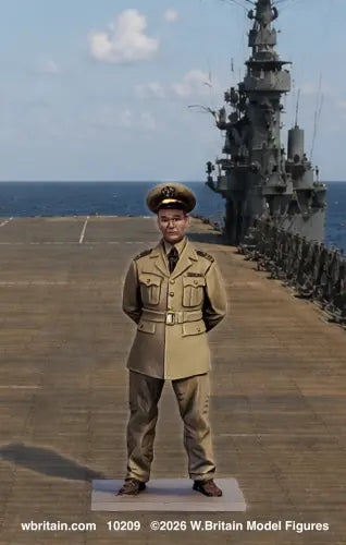 A military model figure of a general in a khaki uniform stands on a deck, with a large gray battleship and ocean in the background. The photo includes a watermark at the bottom.