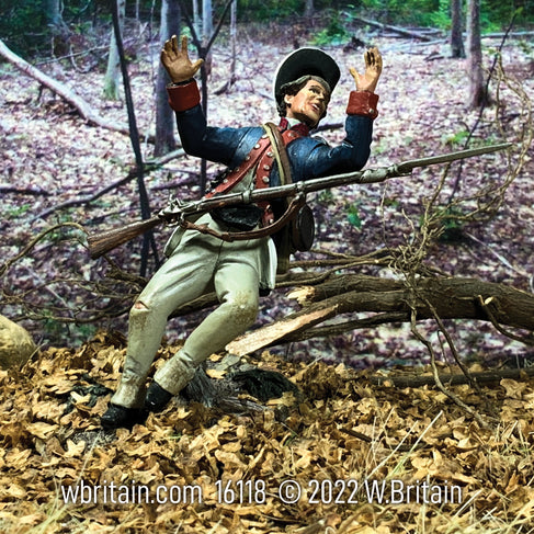 Collectible toy soldier miniature. Soldier is falling to the ground in the forest. Wearing blue jacket and white pants.