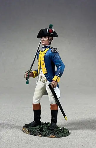 A figure of a toy soldier styled as a colonial military officer stands regally, clad in a blue coat with yellow accents, white pants, and black boots. He holds a sword and dons a black tricorn hat adorned with green and red feathers. The base resembles grass.