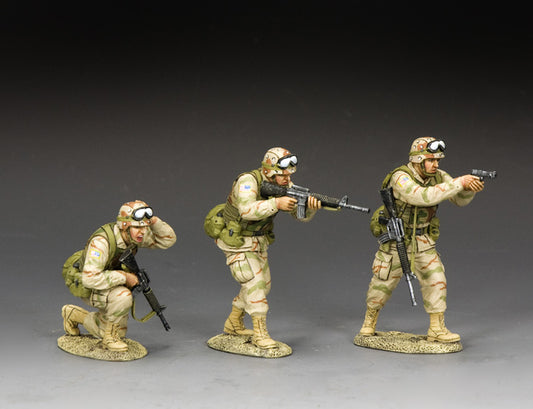 Three toy soldier U.S. Army Rangers in desert camo: one fires a pistol, one advances with M16A2, and one kneels adjusting helmet under fire.
