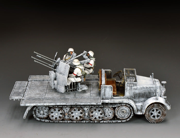 King & Country BBG132 snow-camouflaged Sd.Kfz. 7/1 half-track mounting a quad 20mm Flakvierling gun, crewed by three gunners in white snow suits with red armbands.