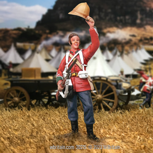 A highly detailed miniature figurine of a British 24th Foot soldier from 1879, shown cheering with his helmet raised in his right hand. He wears a red uniform jacket, blue trousers, and carries a rifle slung over his shoulder. The background features a historical military encampment with tents and wagons, capturing a moment of triumph and camaraderie among the troops.