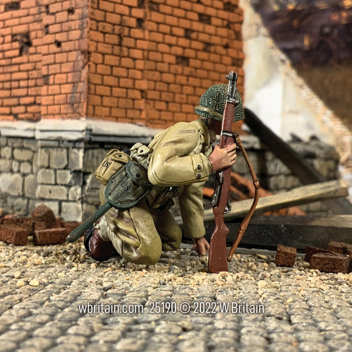 Collectible toy soldier army man U.S. Infantryman Kneeling Watching for Movement. Next to a brick wall.