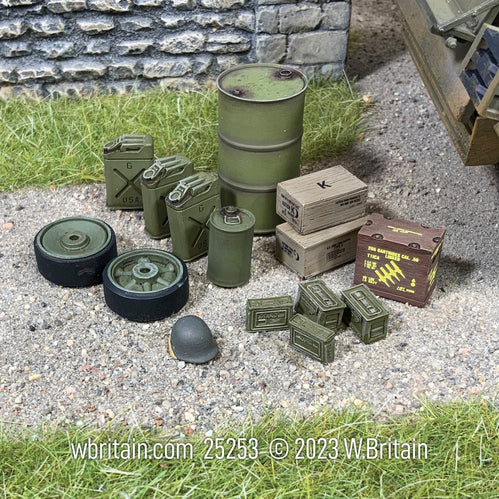 A detailed miniature set depicting U.S. Armor accessories from World War II. The set includes a 55-gallon fuel drum, several 'Jerrycans', lubrication cans, a wooden box of .50 caliber linked ammo, Sherman tank road wheels, .30 and .50 caliber ammo cans, boxes of C and K rations, and a military helmet. The items are arranged on a gravel and grass surface next to a stone wall, highlighting their use in historical military logistics.