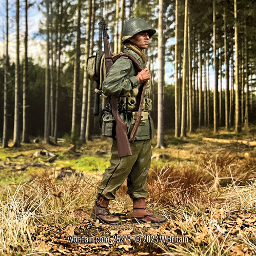 A highly detailed 1/30 scale toy soldier figurine representing a U.S. Infantryman from the 442nd Infantry Regiment during 1943-45. The figurine is set in a realistic outdoor environment with a forest background. The soldier is wearing a World War II era uniform, complete with a helmet, backpack, and holding a rifle. The scene captures the soldier standing in a clearing among trees, ready for action.