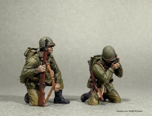 Reporting In. Two miniature soldiers in World War II uniforms kneel on one knee. One soldier holds a rifle while the other is using a radio. Both wear helmets and backpacks.