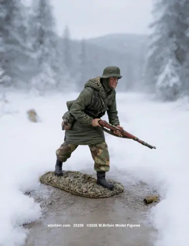 A detailed scale model figurine of a World War II German soldier in winter camouflage, posed in a snowy forest setting on a muddy base with a rifle.