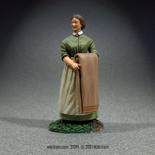 Miniature Figure of a lady with long dress and folded blanket.