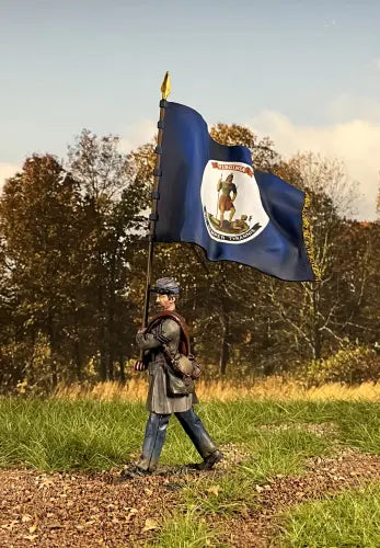 A miniature figurine of a soldier holding a large Virginia state flag on a flagpole, wearing historical military attire. He is on the battlefield.