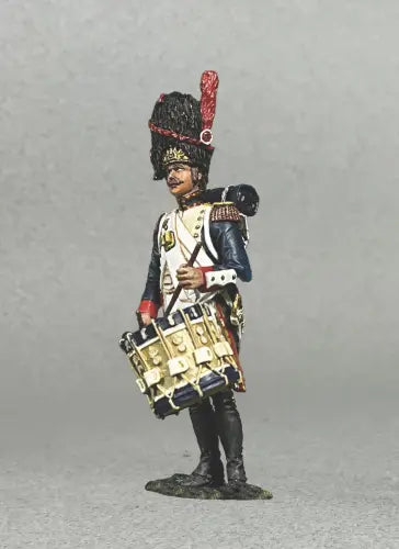 A miniature toy soldier figurine model of a Napoleonic French soldier dressed in a white and blue uniform with red accents. The soldier holds a drum and wears a tall bearskin hat with a red plume. The background is a plain gray.