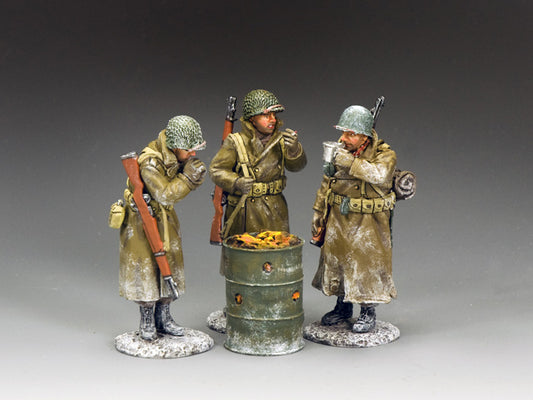 Three toy soldiers WWII U.S. soldiers in winter gear warm up around a burning oil drum, drinking coffee and smoking during the Battle of the Bulge.