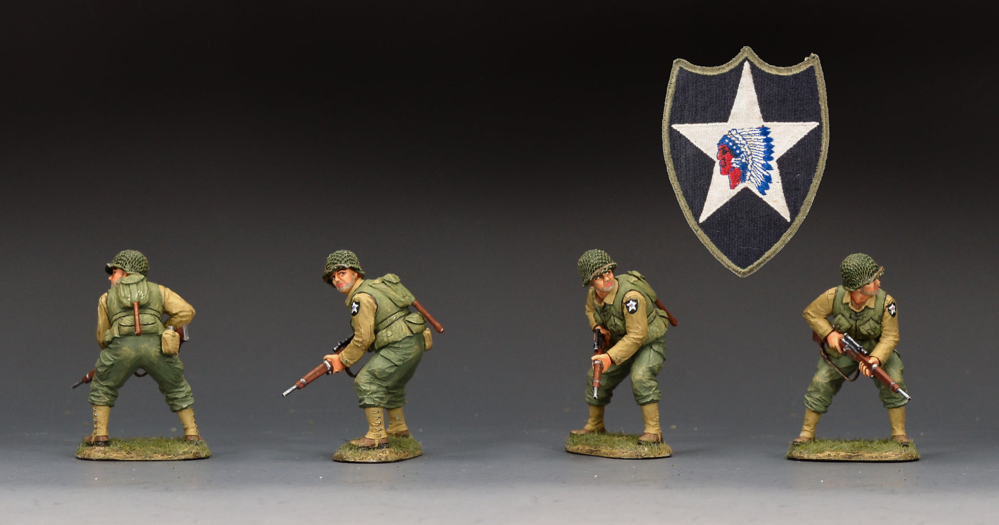 Four painted military figurines in olive drab and tan uniforms posed across a dark studio background, with a shield emblem featuring a white star and red-and-blue feather detail above them.