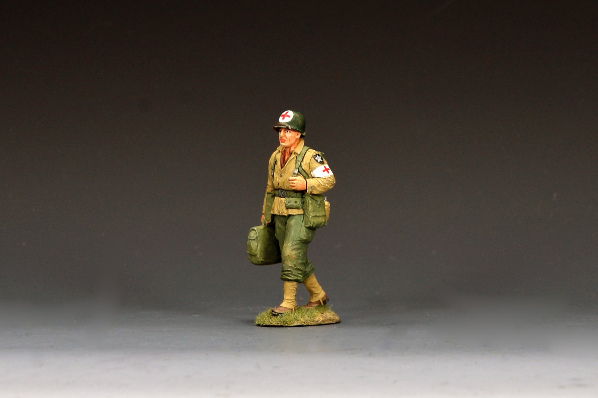 King & Country DD405 figure of an unarmed U.S. Army medic walking with a medical bag, a red cross on his helmet and a Red Cross armband, Indian Head patch on his shoulder.