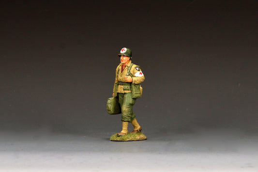 King & Country DD405 figure of an unarmed U.S. Army medic walking with a medical bag, a red cross on his helmet and a Red Cross armband, Indian Head patch on his shoulder.