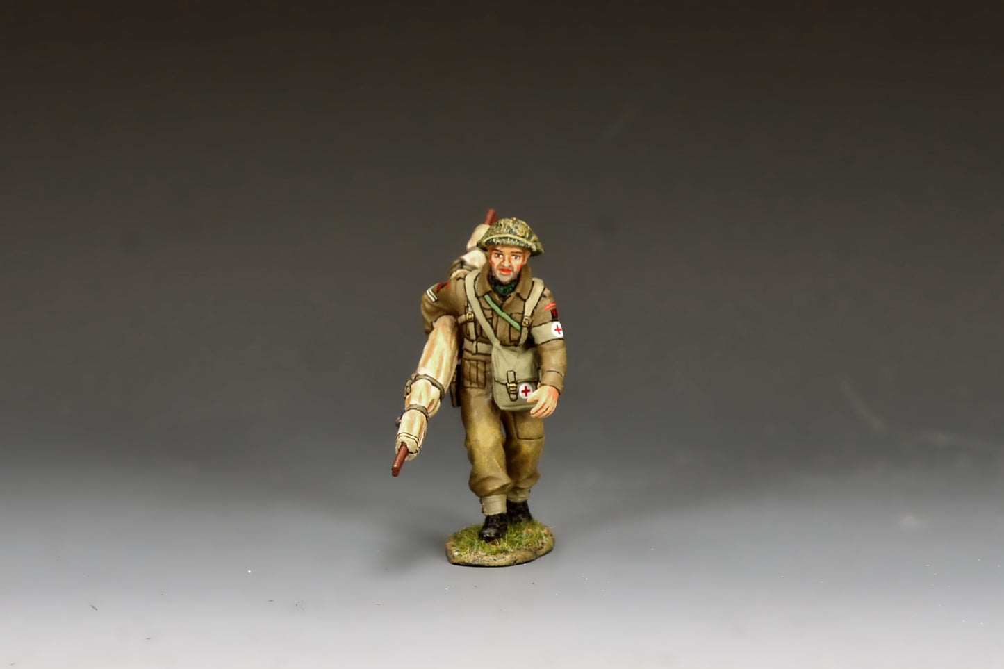 King & Country Gold Beach Medic with Stretcher, RAMC corporal in MkII helmet with scrim and Red Cross brassard, folded stretcher over shoulder, D-Day Normandy 1944, 1/30 60mm matte figure, DD416