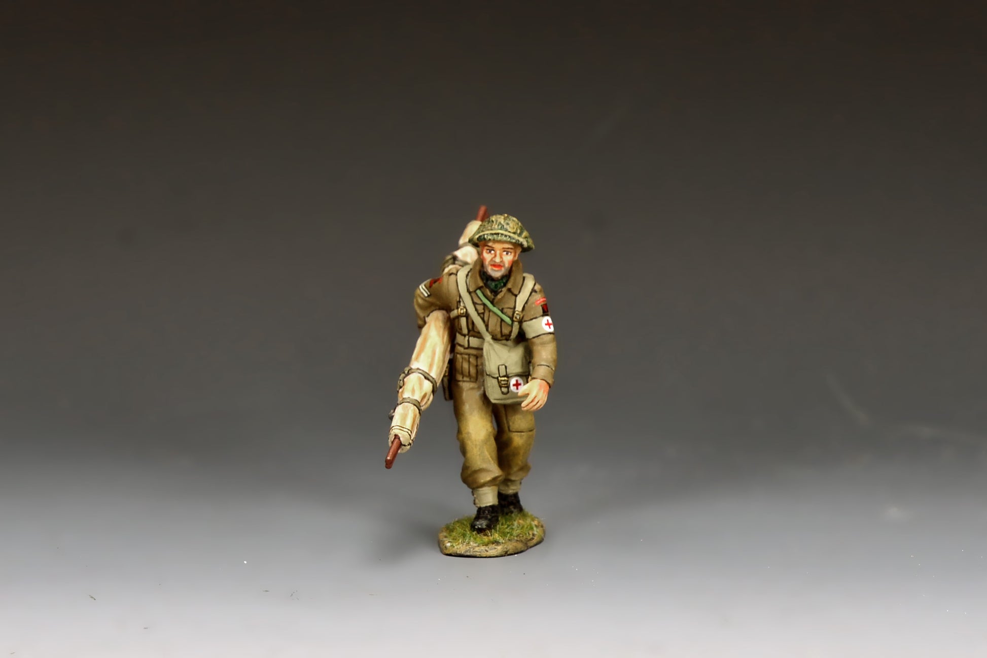 King & Country Gold Beach Medic with Stretcher, RAMC corporal in MkII helmet with scrim and Red Cross brassard, folded stretcher over shoulder, D-Day Normandy 1944, 1/30 60mm matte figure, DD416