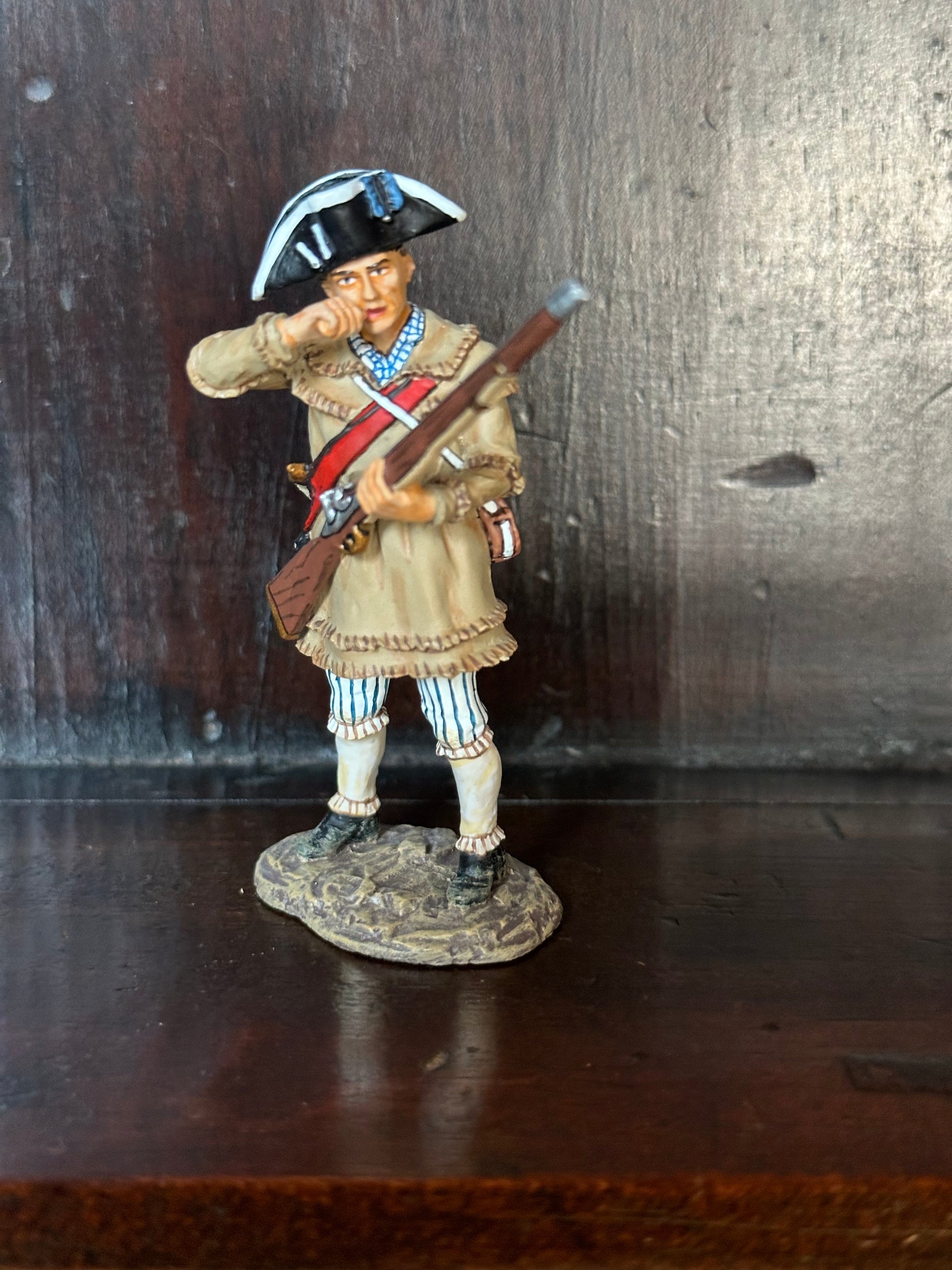 Collectible toy soldier miniature army men Rifleman Biting Cartridge. Displayed on a book shelf.