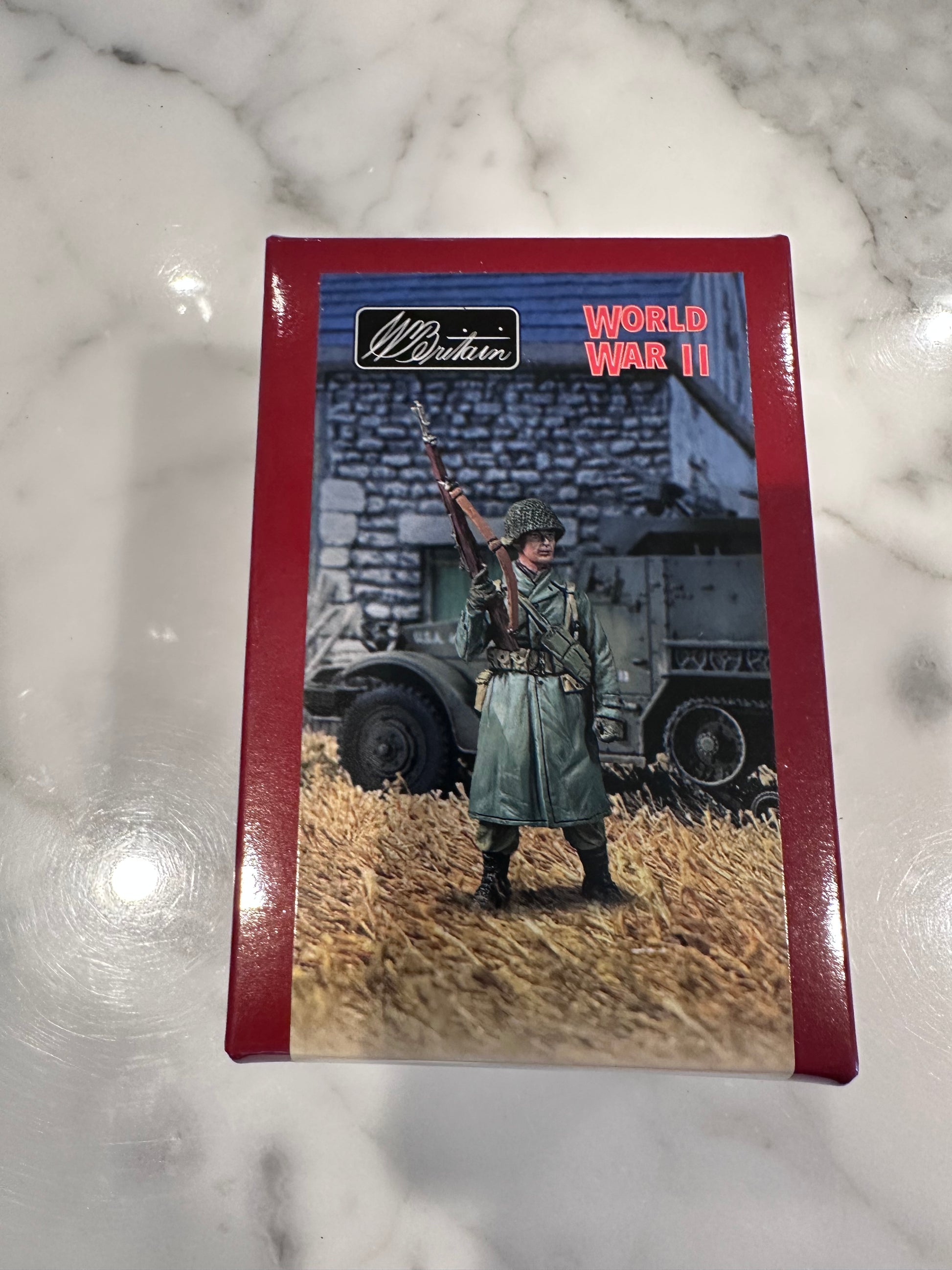 Card with a soldier and tank illustration on a red border, placed on a marble surface.