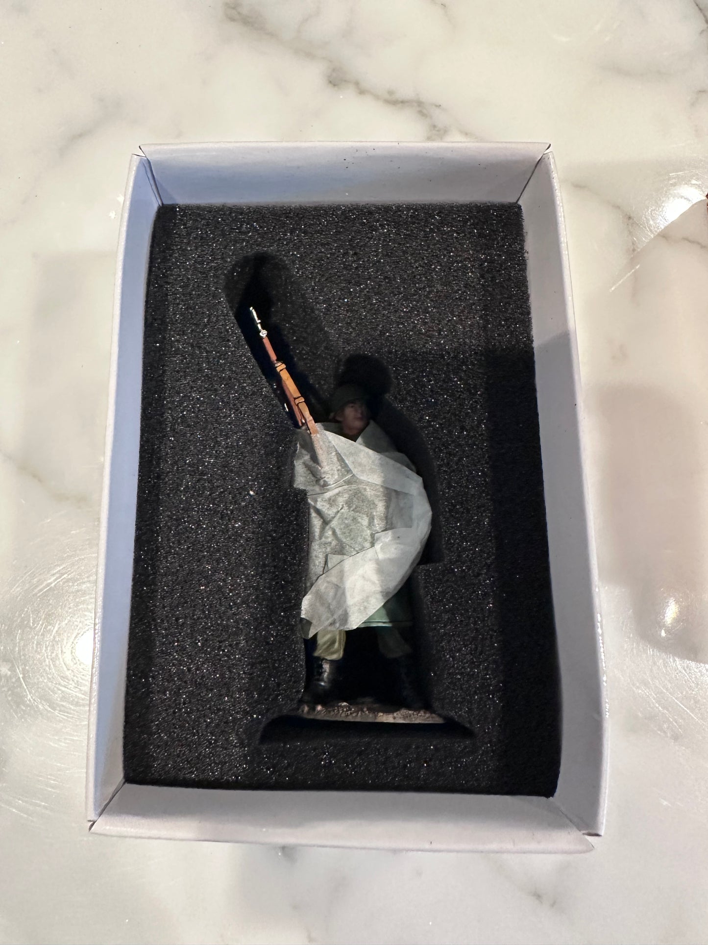 Toy Soldier in a box on a marble surface