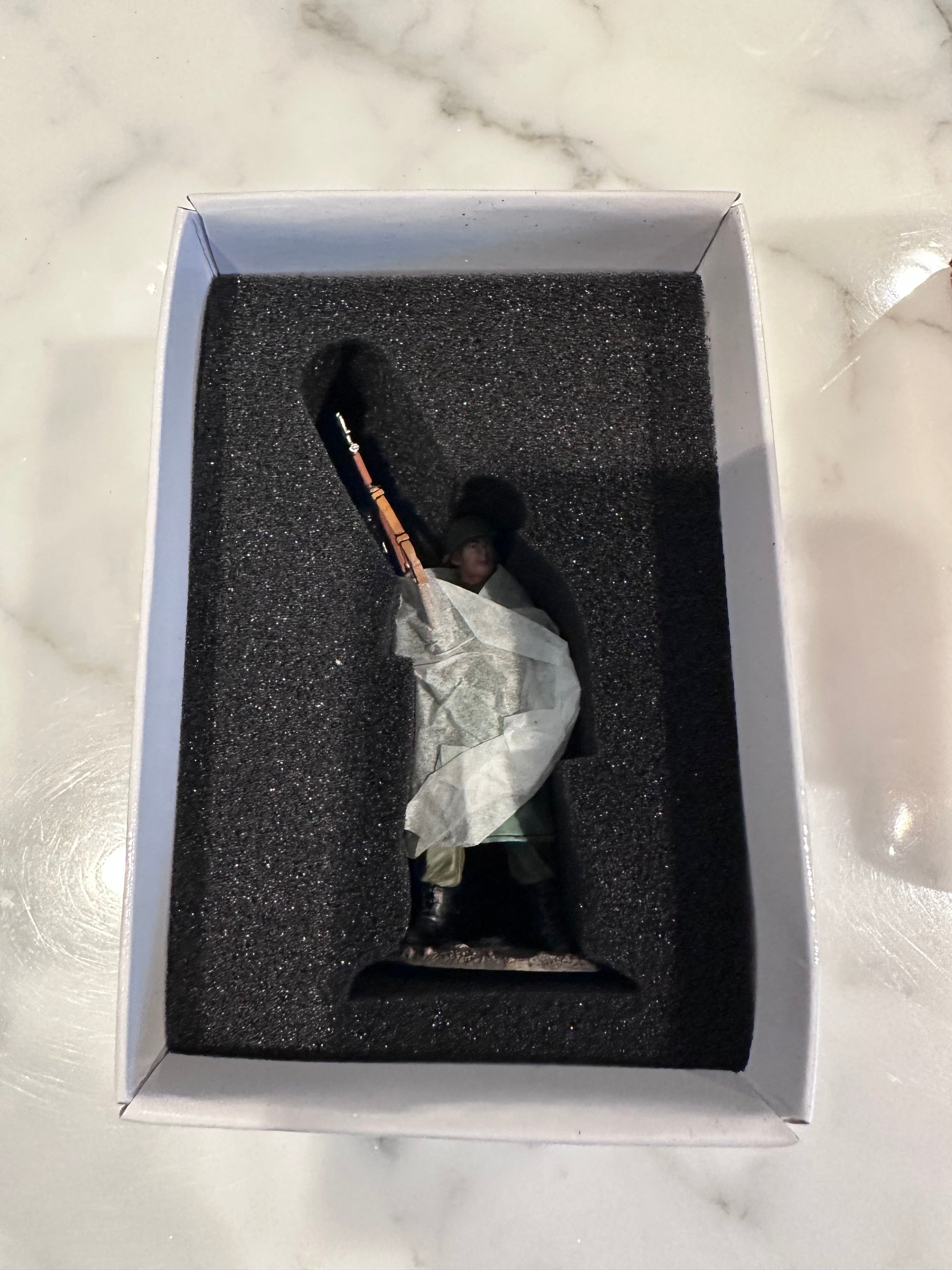 Toy Soldier in a box on a marble surface