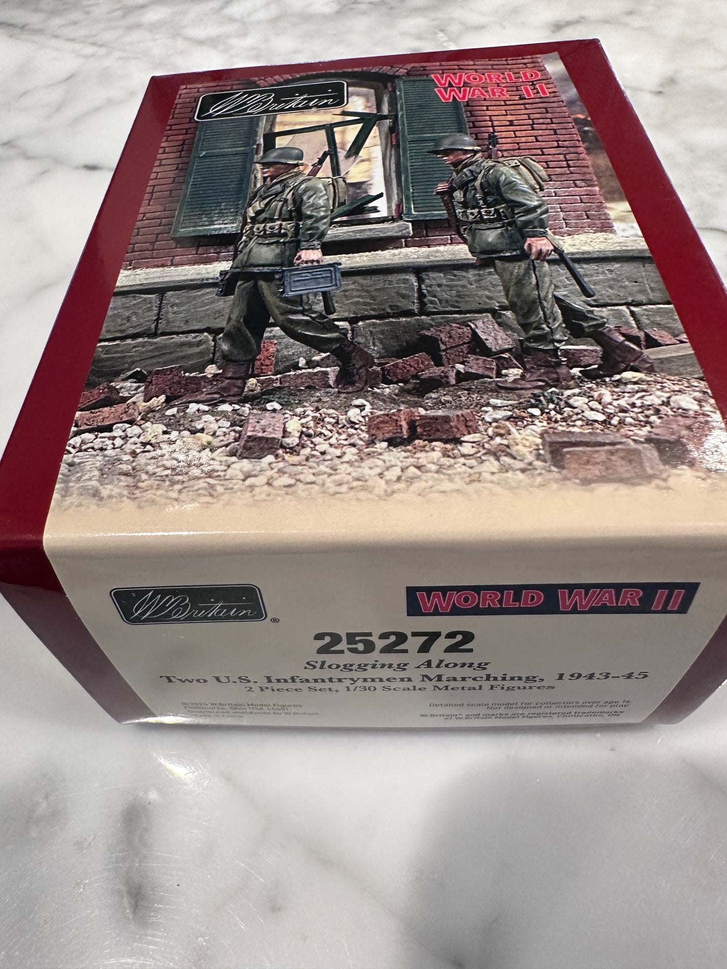 toy soldier model kit box with soldiers and terrain on a marble surface