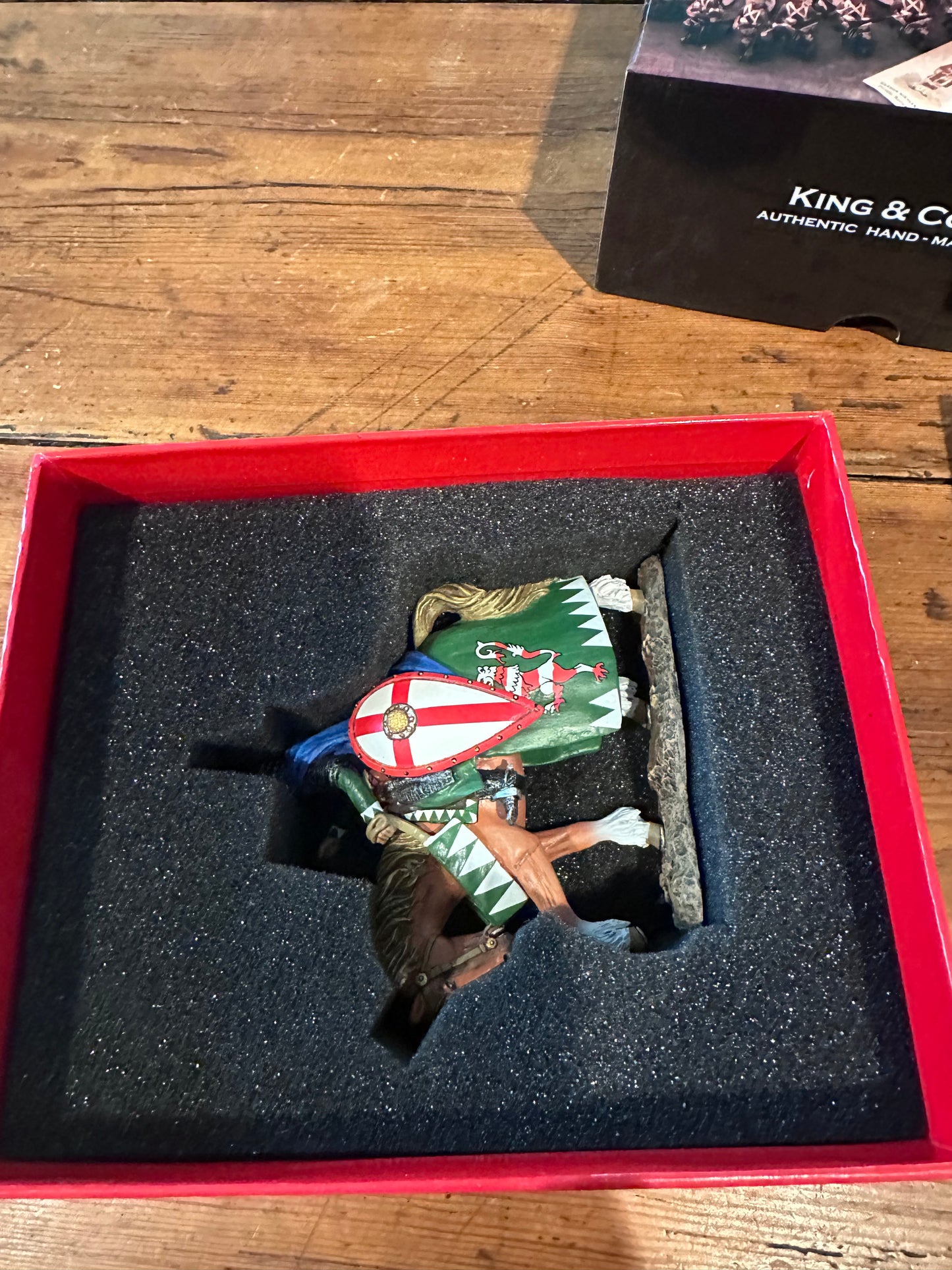 Toy Soldier Model of a horse with flags in a collector's red box on a wooden surface