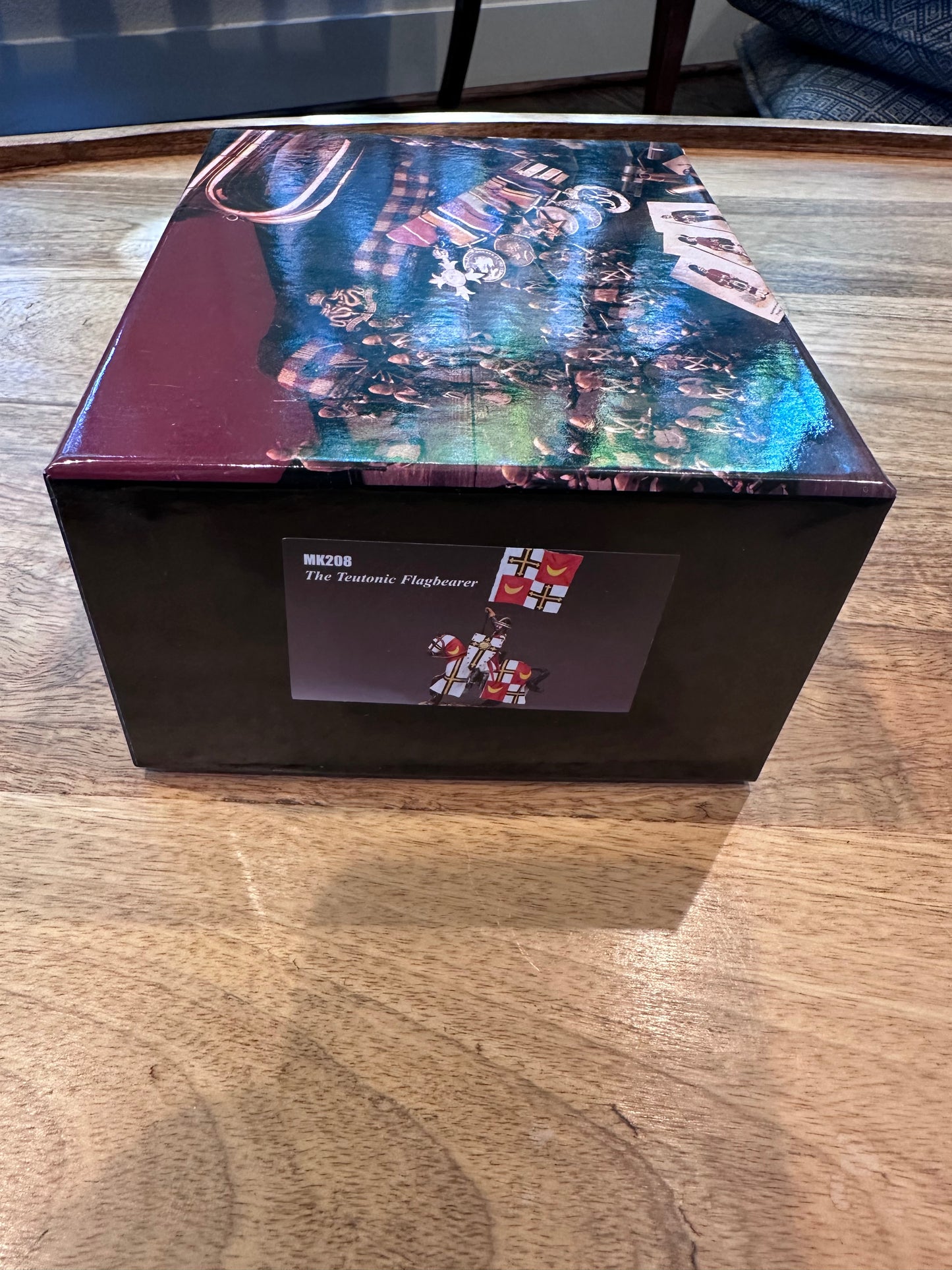 Hexagonal box with colorful design on a wooden surface packaging for toy soldier The Teutonic Flagbearer.