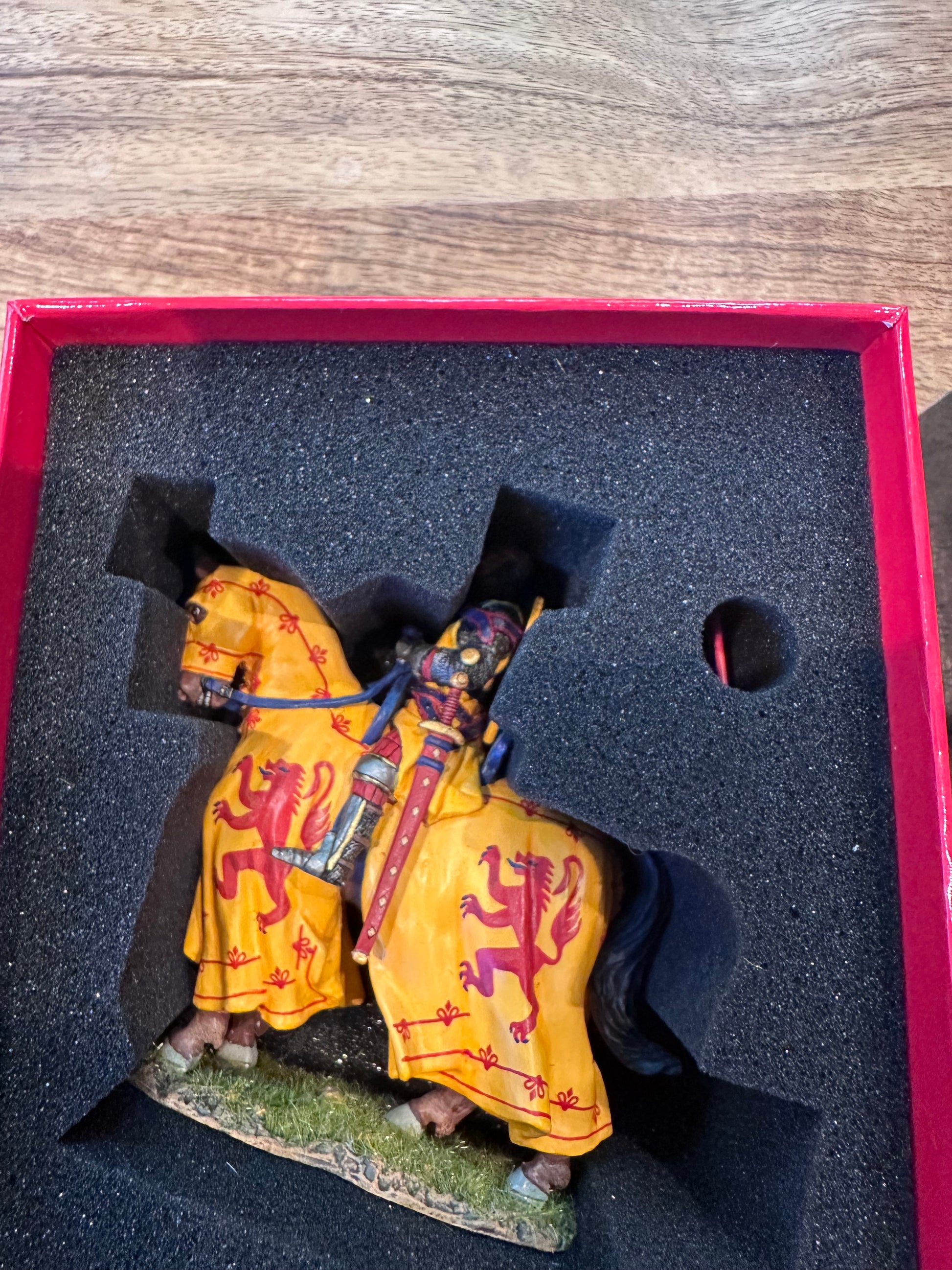 toy soldier King Robert I of Scotland Yellow fabric item with red patterns in a black foam-lined box on a wooden surface