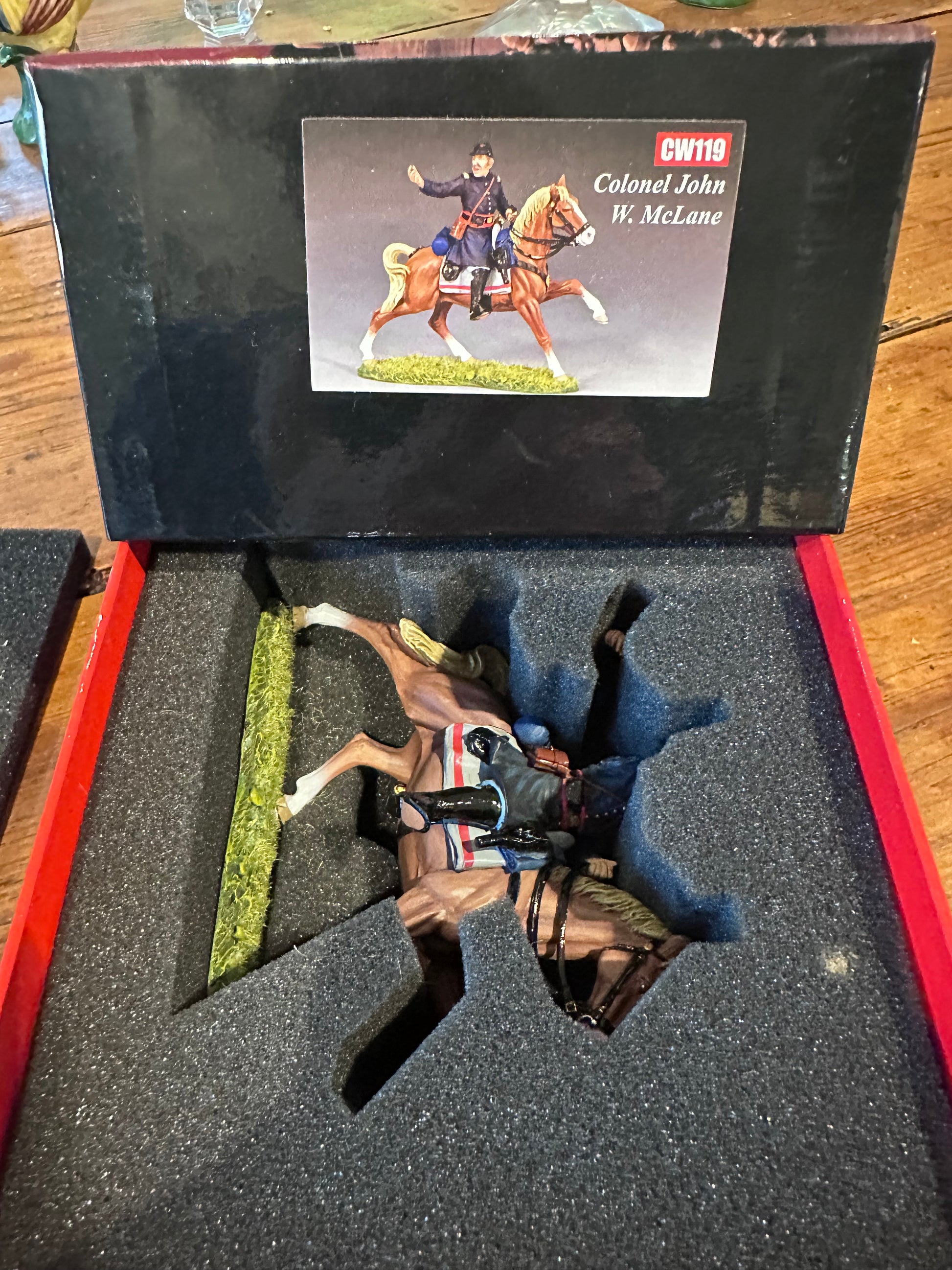 Model figure of a soldier on horseback in a display case with a box showing product details.