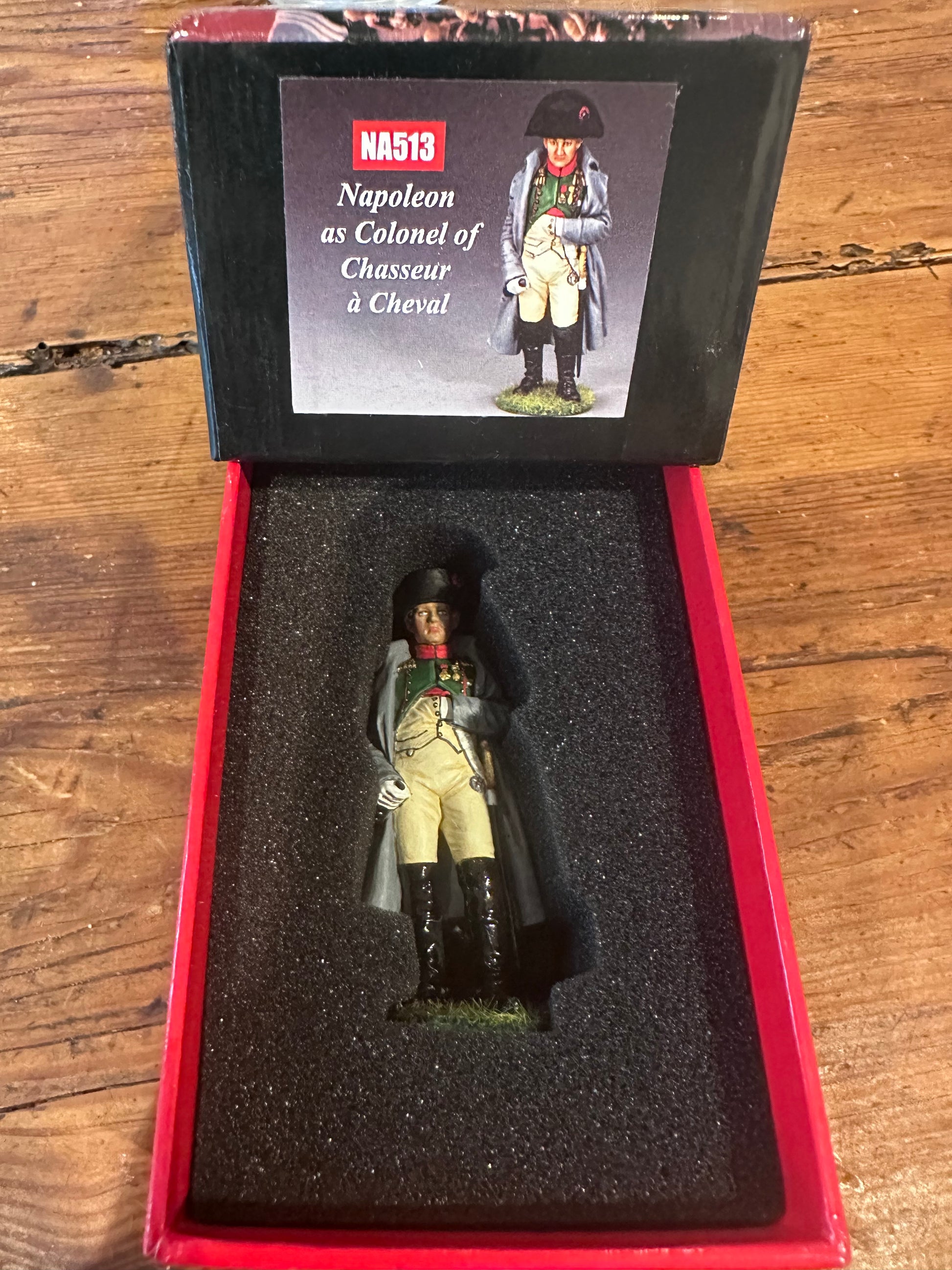 Model figure of a Napoleon in a display case with a label on a wooden surface