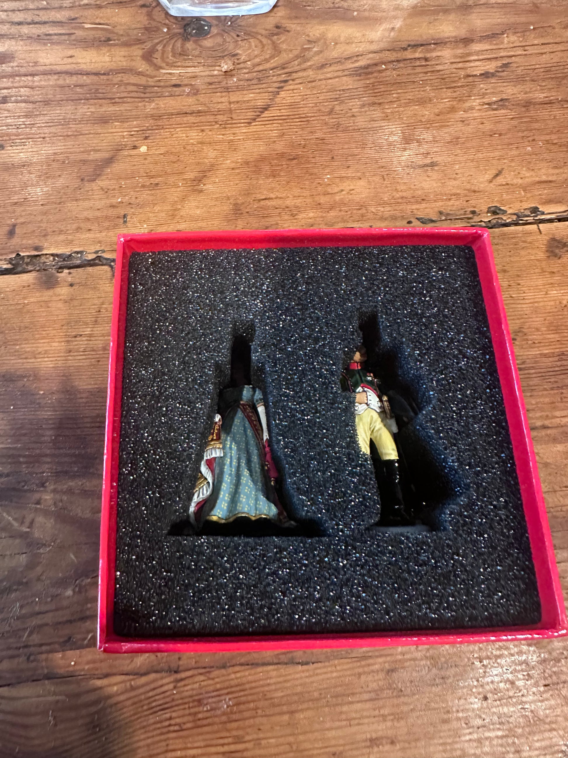 Two toy soldier figurines Napoleon and Josephine in a red box on a wooden surface