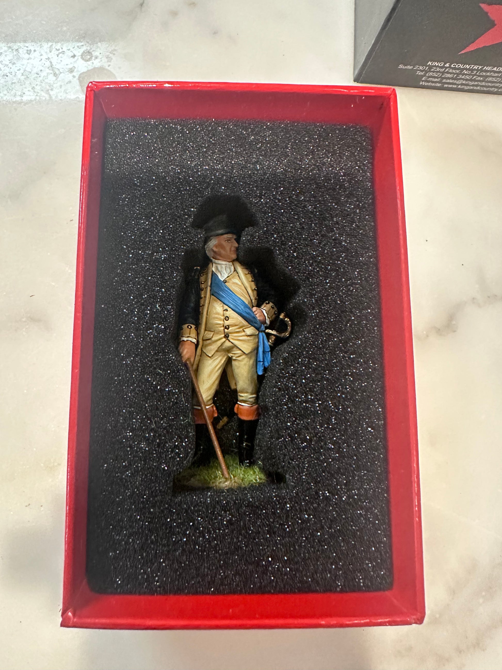 Model George Washington figure  in a red box on a marble surface