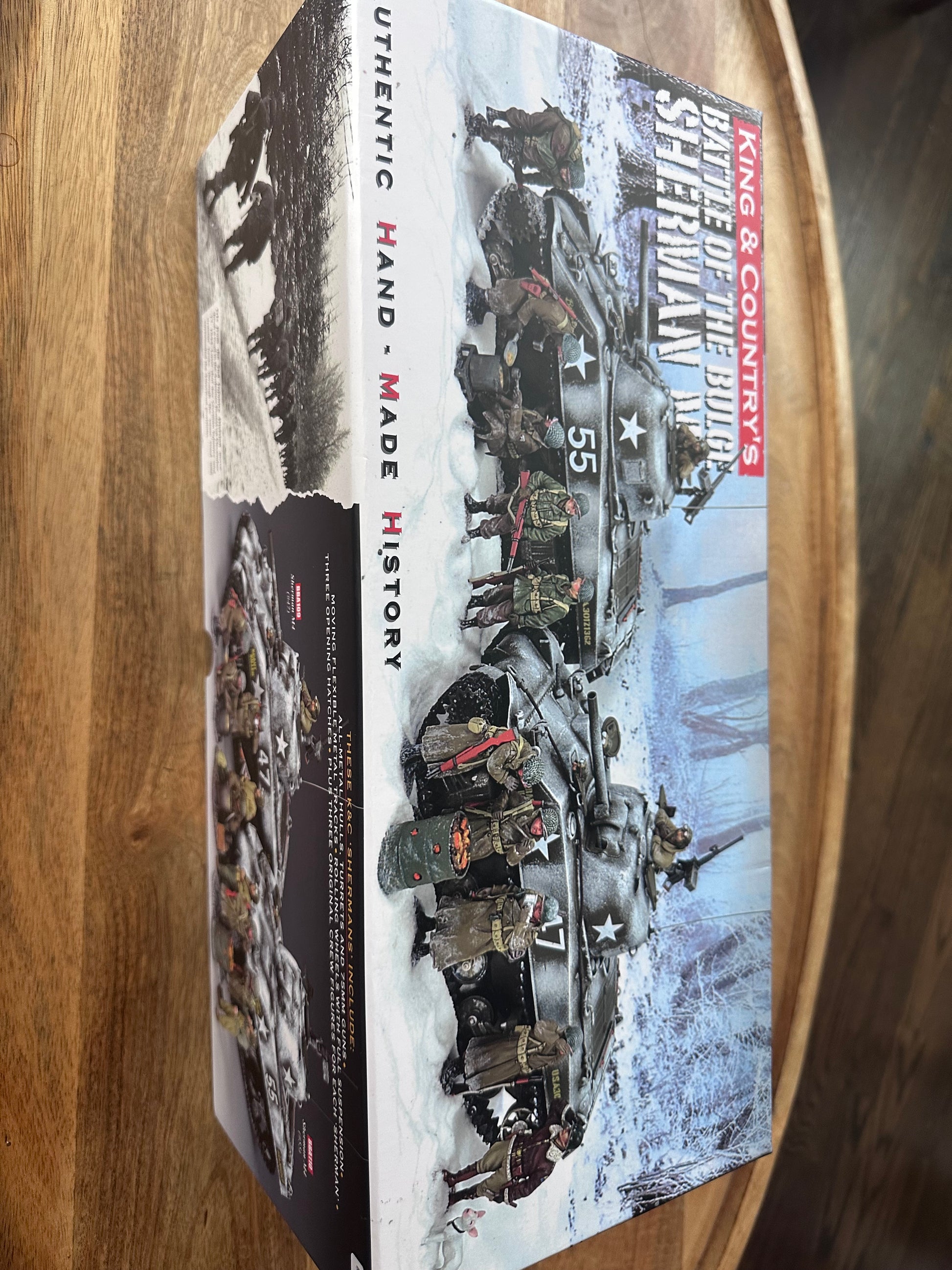 Model kit packaging for 'Battle of the Bulge Sherman' by King & Country on a wooden surface.