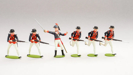 Six toy soldiers are lined up in uniform outfits of blue, red, and white with black hats. The central figure holds a sword, while the others have rifles with bayonets. They are standing on green bases against a plain background.