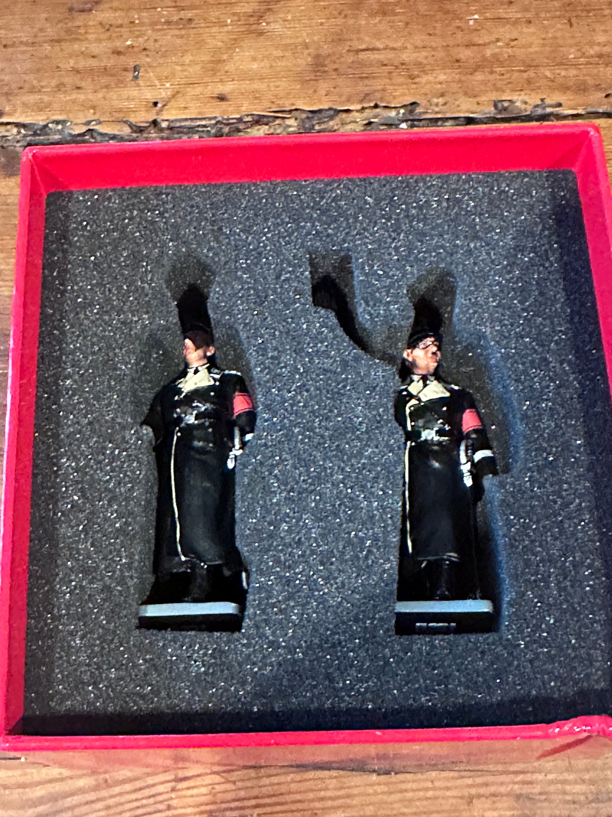 Two toy soldier figures in a display case on a wooden surface