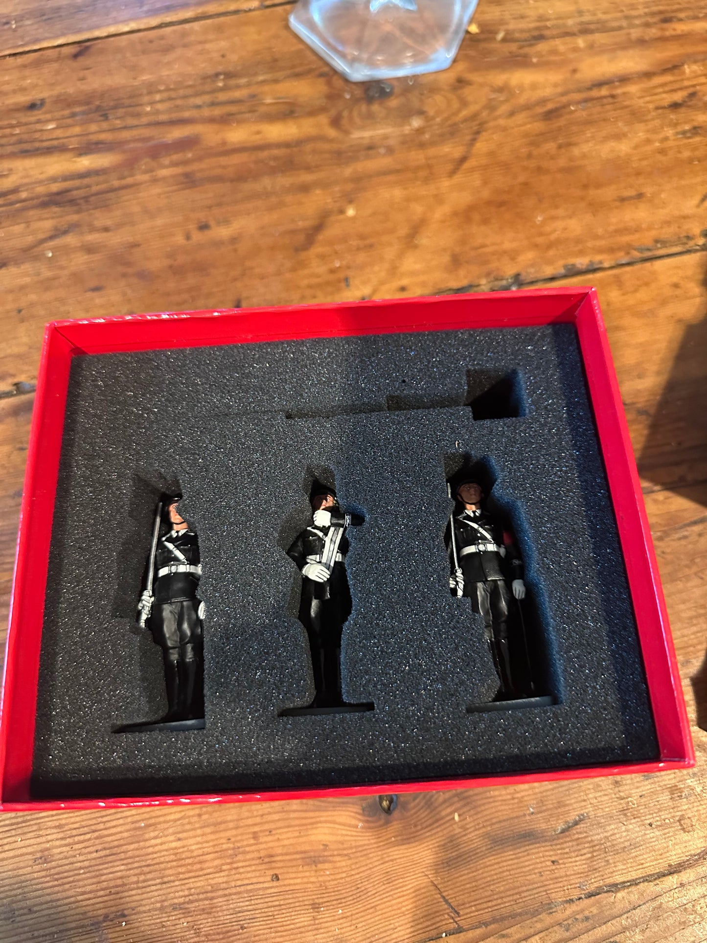 Three toy soldier figures in a red box on a wooden surface