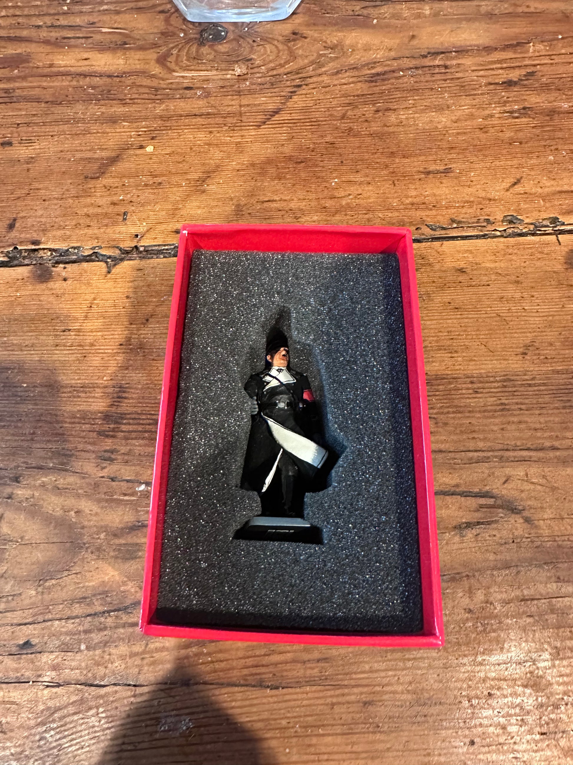 Figurine of toy soldier Sepp Dietrich in a red box on a wooden surface.