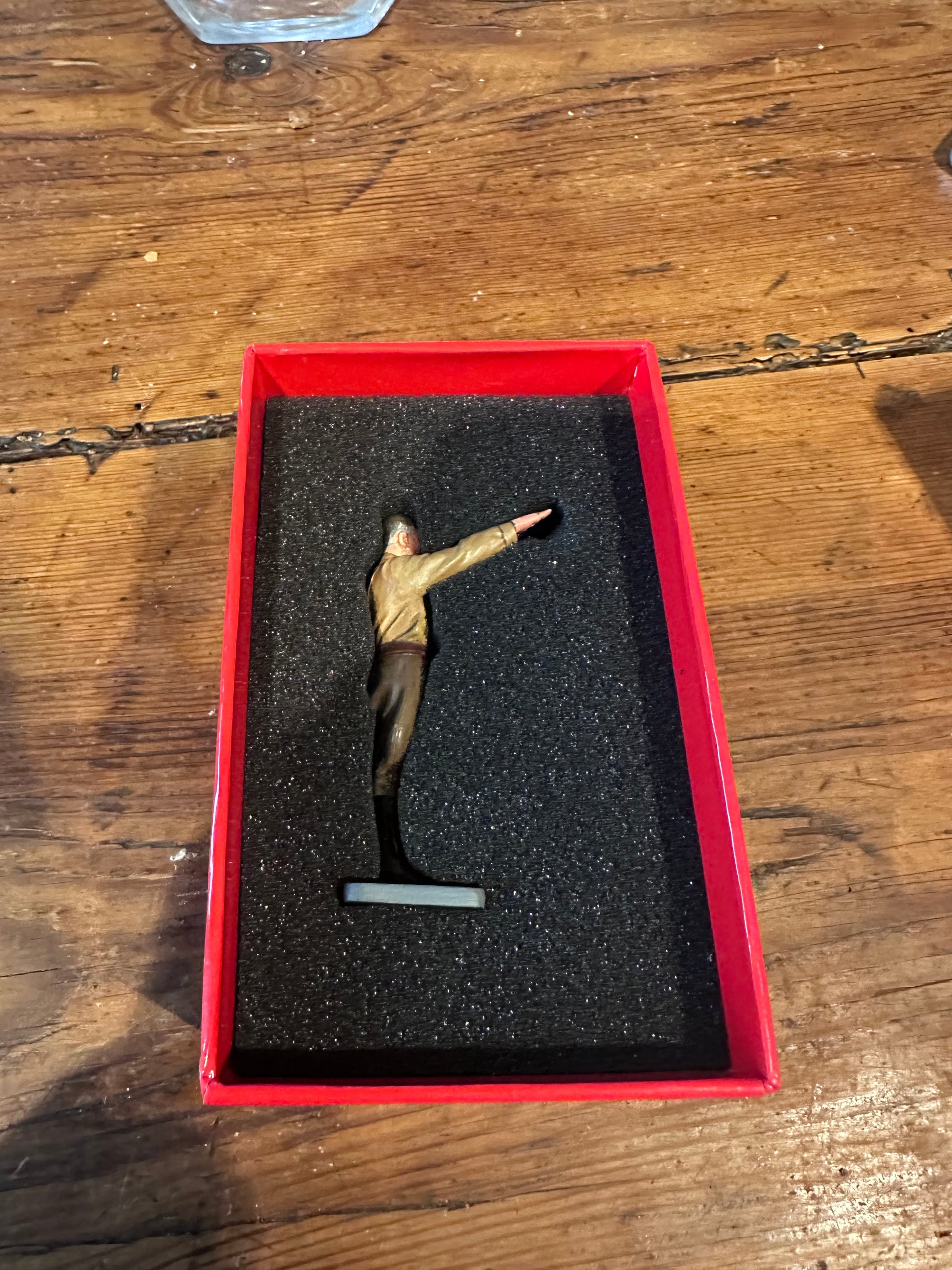 Small figurine of Hitler in a red box on a wooden surface
