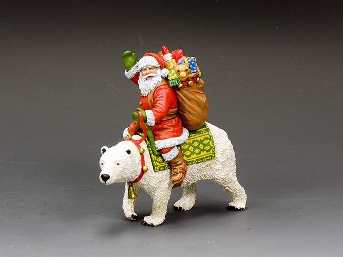 Santa figurine riding a festive polar bear with a green saddle and a toy-filled gift sack, hand-painted in bright holiday colors.