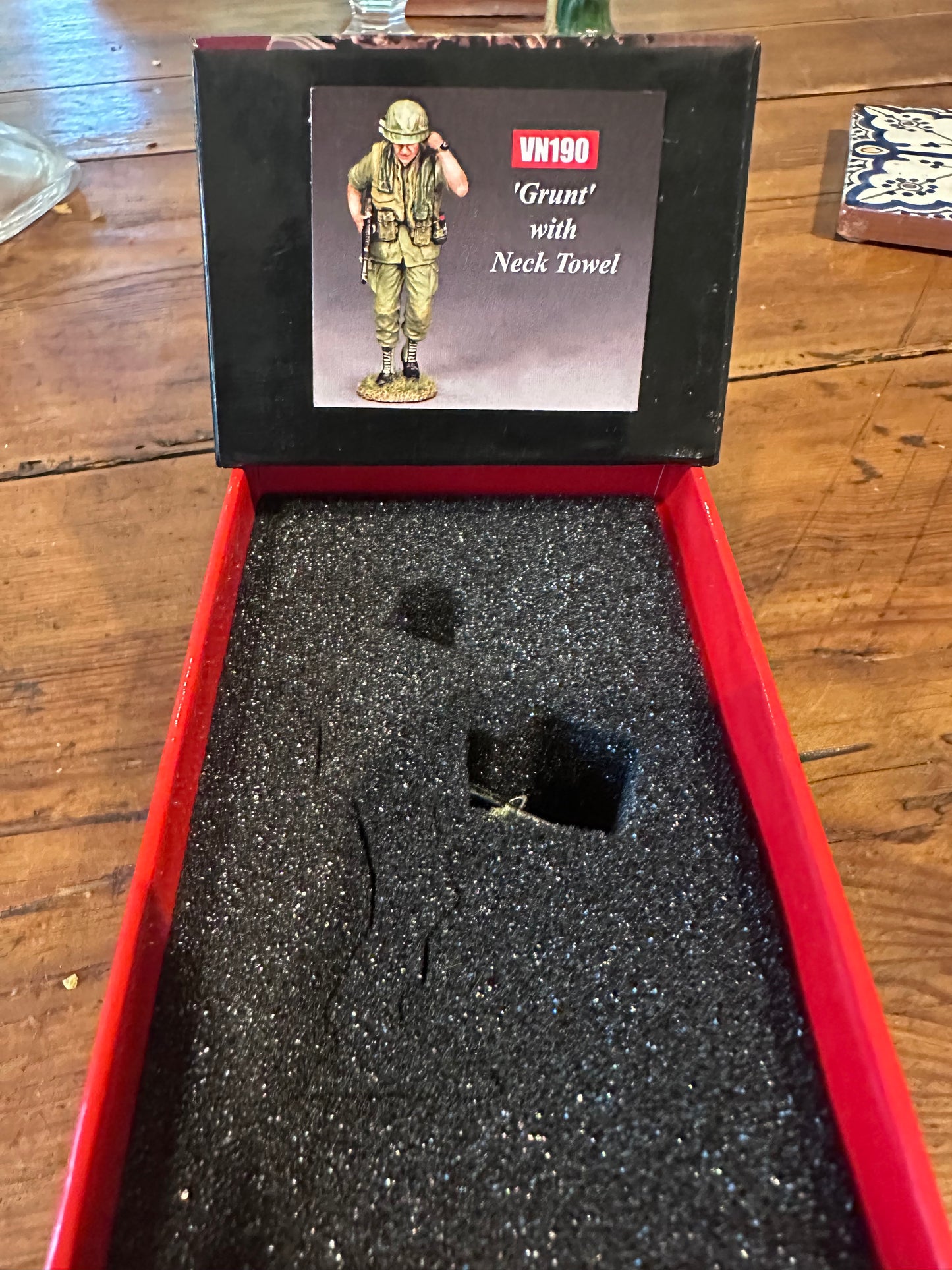 Toy figure The Walking Grunt in a red box with a black label on a wooden surface