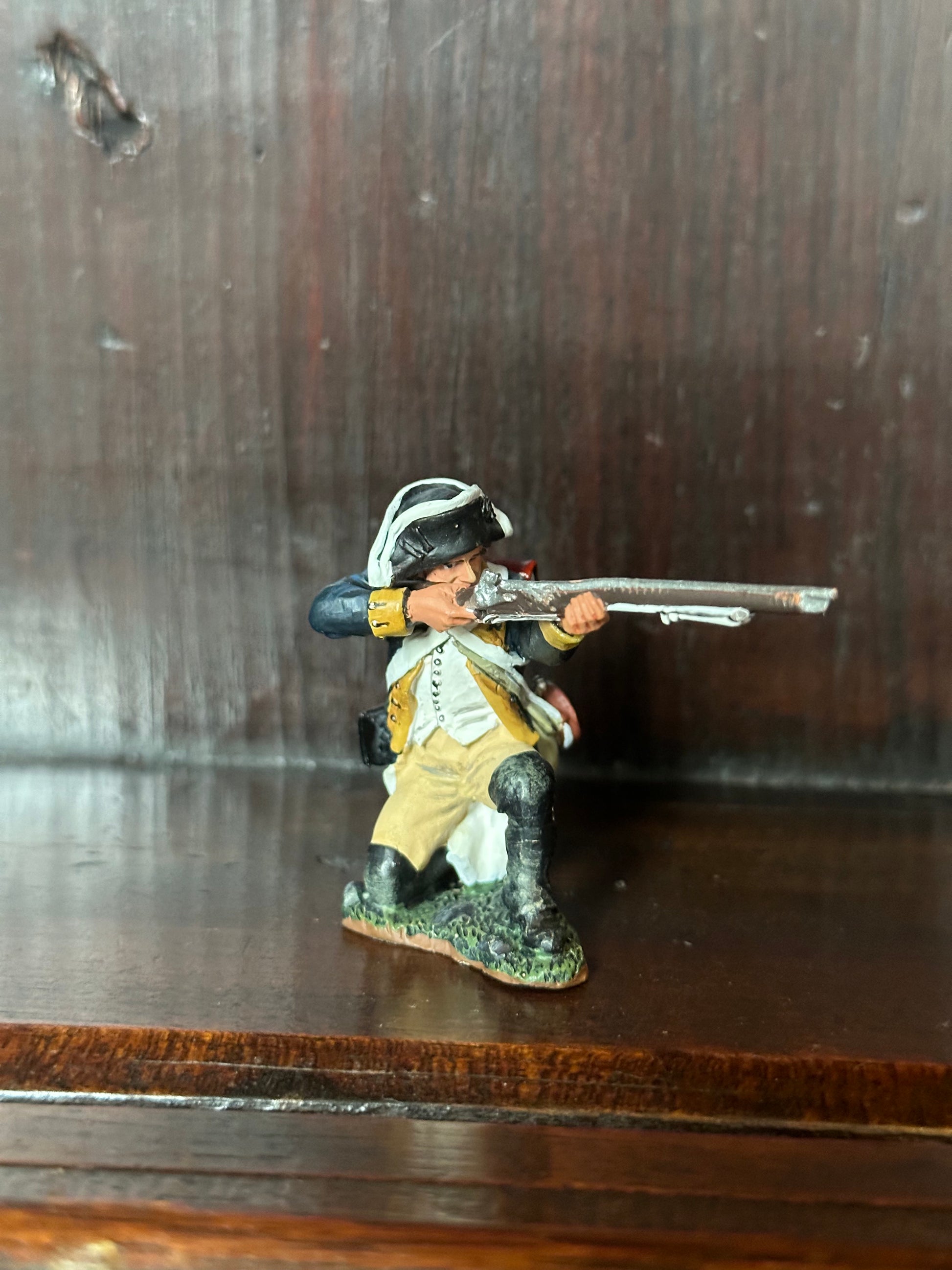 Collectible toy soldier miniature army men Kneeling Firing Rifle. On a book shelf.