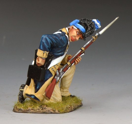 A miniature military figurine of a soldier in colonial-era uniform kneels on one knee, holding a rifle with a bayonet. The soldier wears a blue coat, beige pants, and a blue cap, set against a neutral background.